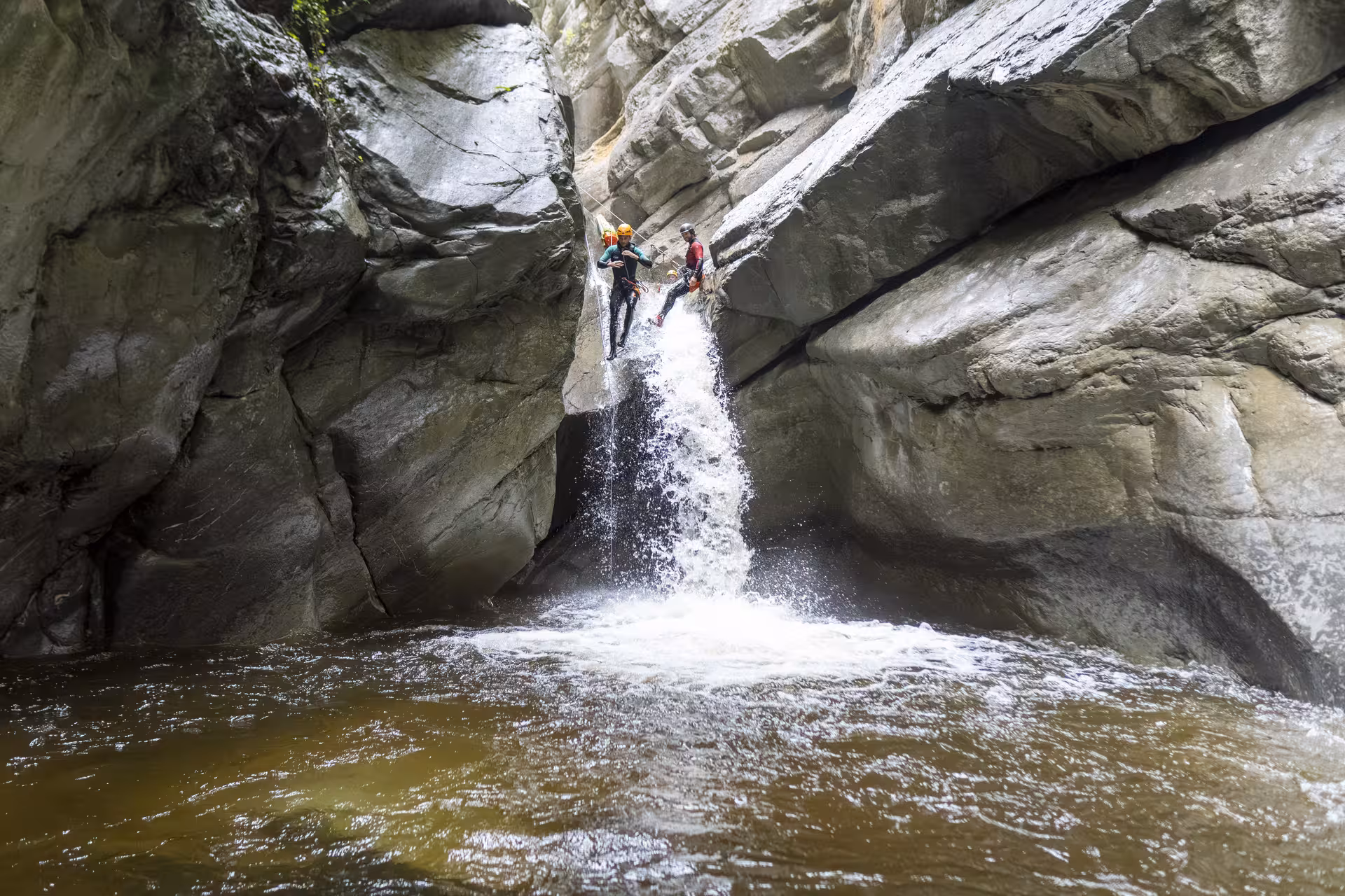 Adventurers rappel down a waterfall during canyoning at Chli Schliere near Luzern, showcasing thrilling outdoor fun.