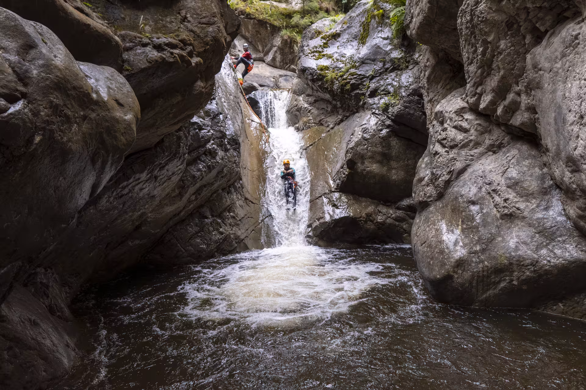 Thrilling canyoning descent through a cascading waterfall in the rugged Chli Schliere gorge near Luzern.