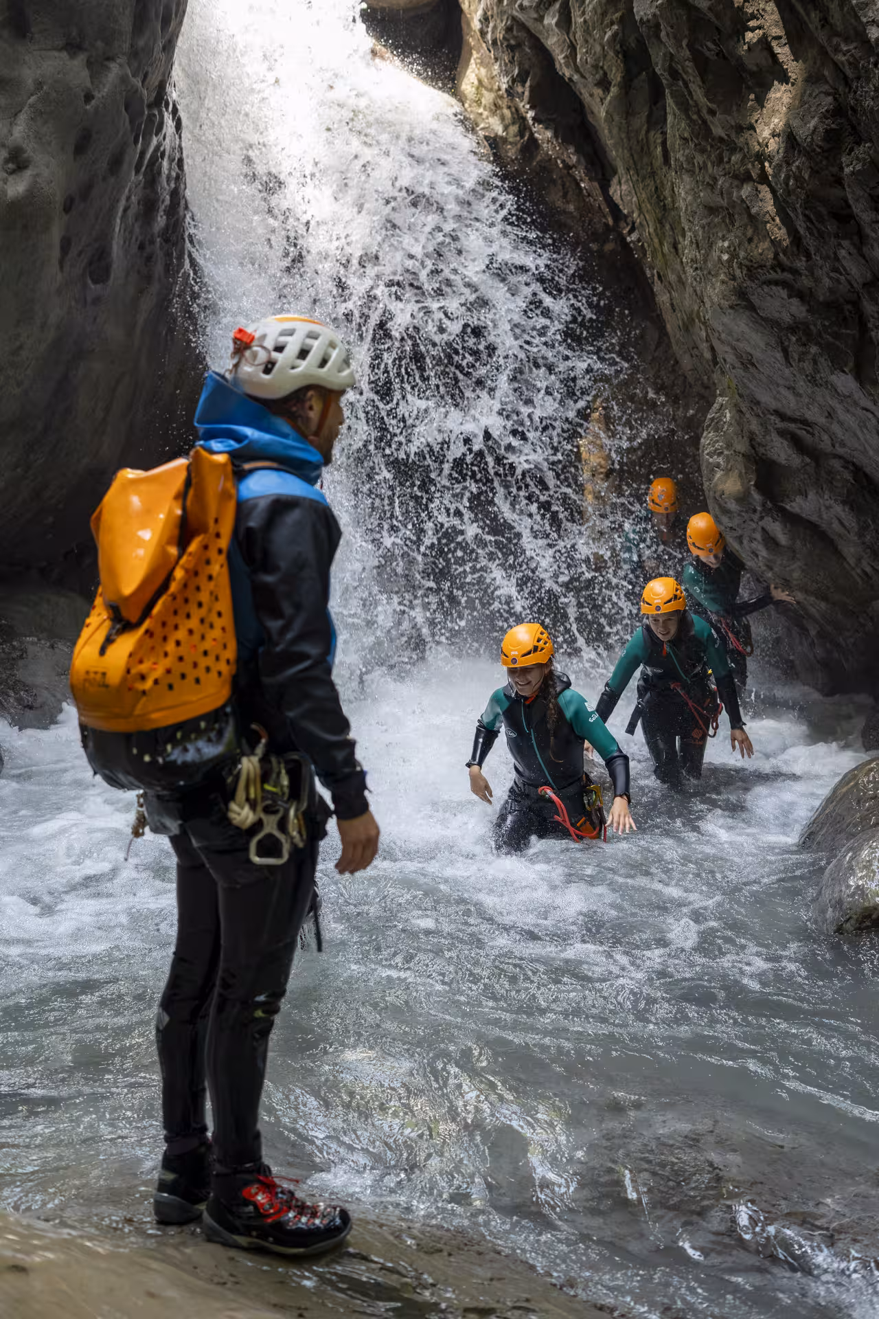 Adventurers in wetsuits navigate a waterfall during a thrilling canyoning experience in Interlaken.