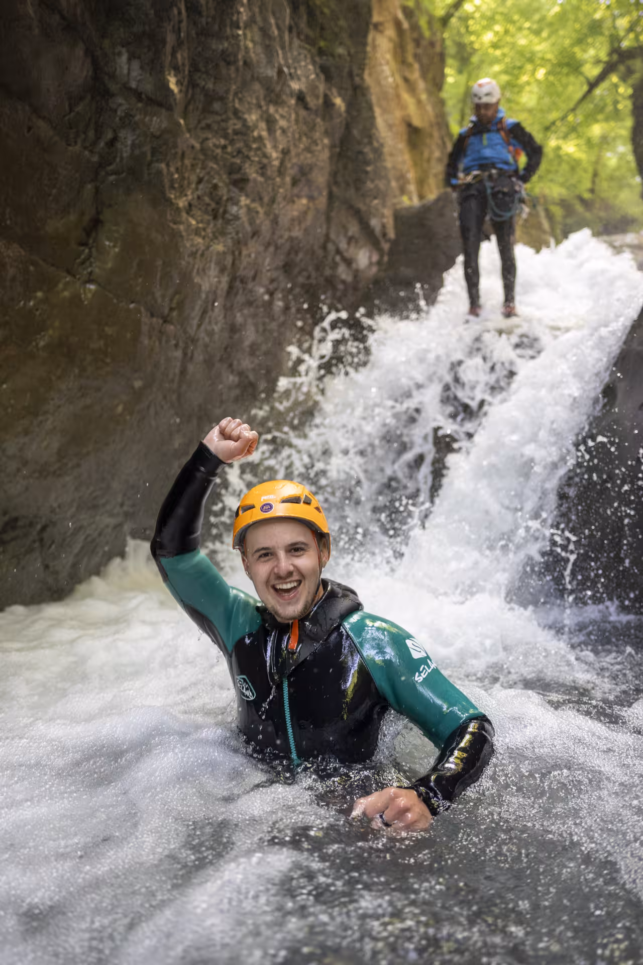 Excited participant triumphs in waterfall plunge during Canyoning Interlaken tour, showcasing exhilarating outdoor fun.