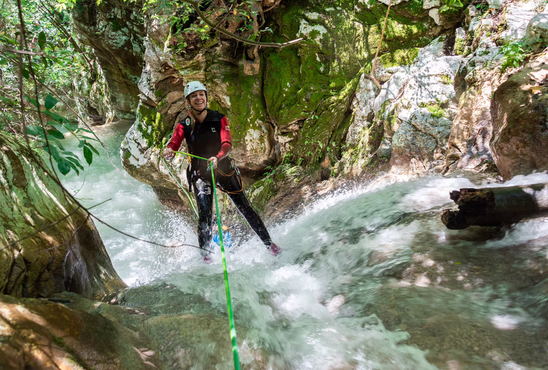 Canyoning at Neda Waterfalls with guided rope descent through rushing stream in a mossy rocky gorge
