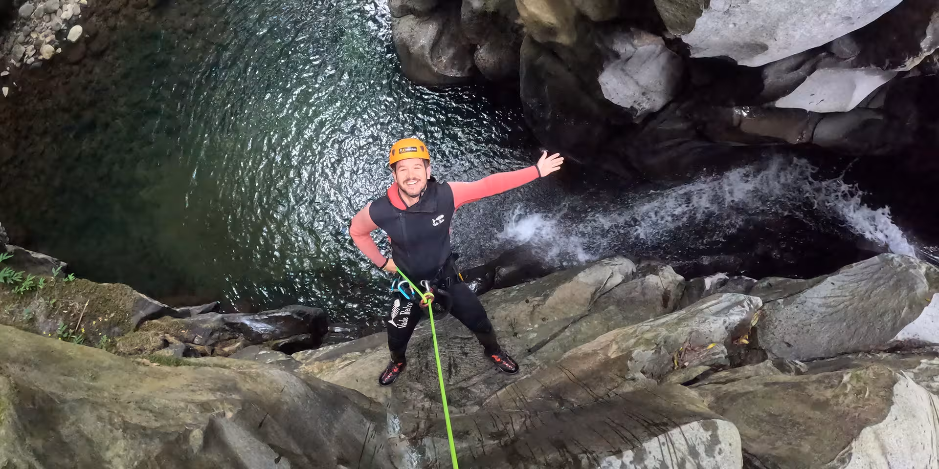 Canyoning rappel above rocky gorge and emerald pool at Salto do Cabrito, São Miguel Azores guided tour