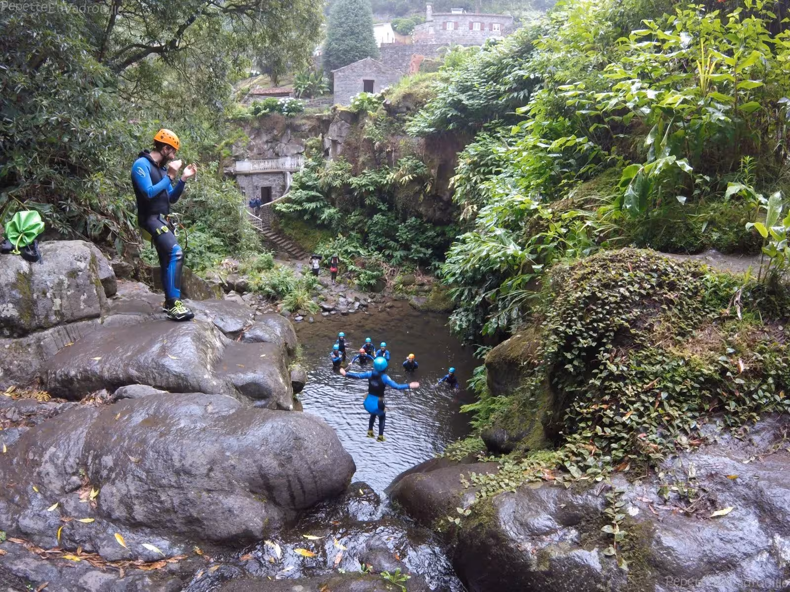 Canyoning group jumping into natural pool at Ribeira dos Caldeirões waterfall canyon, São Miguel Azores
