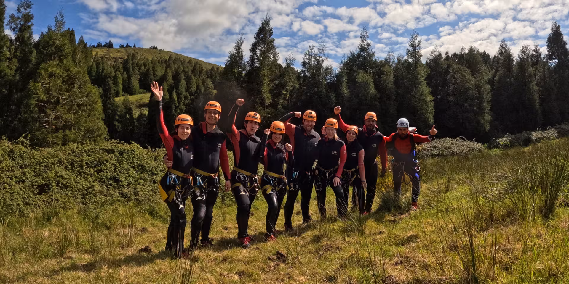 Canyoning Outward Shore group in wetsuits and helmets posing in lush forest before the canyon adventure