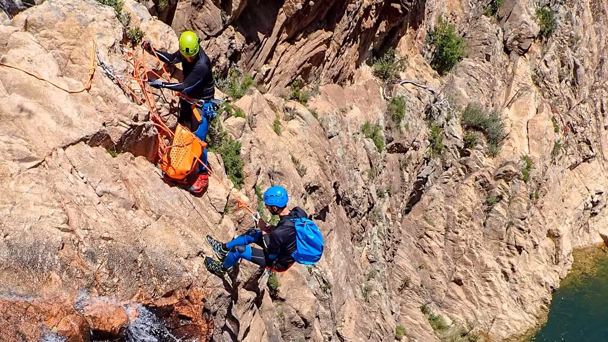 Adventurers canyoning at Rio Pitrisconi, San Teodoro, navigating rocky cliffs with safety gear and vibrant helmets.