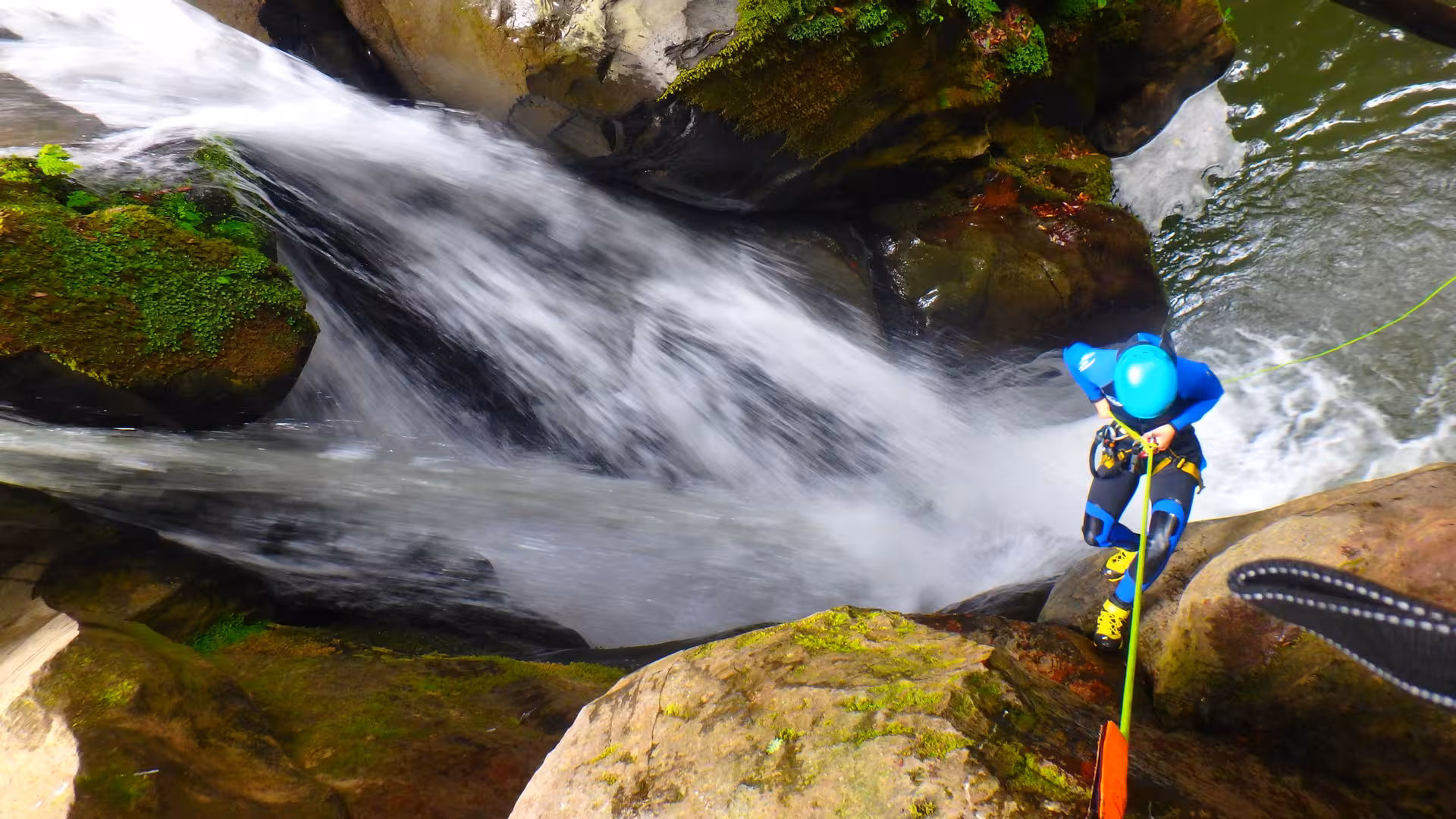 Canyoner rappelling down wet rock next to Salto do Cabrito cascade, São Miguel Azores half-day with transport