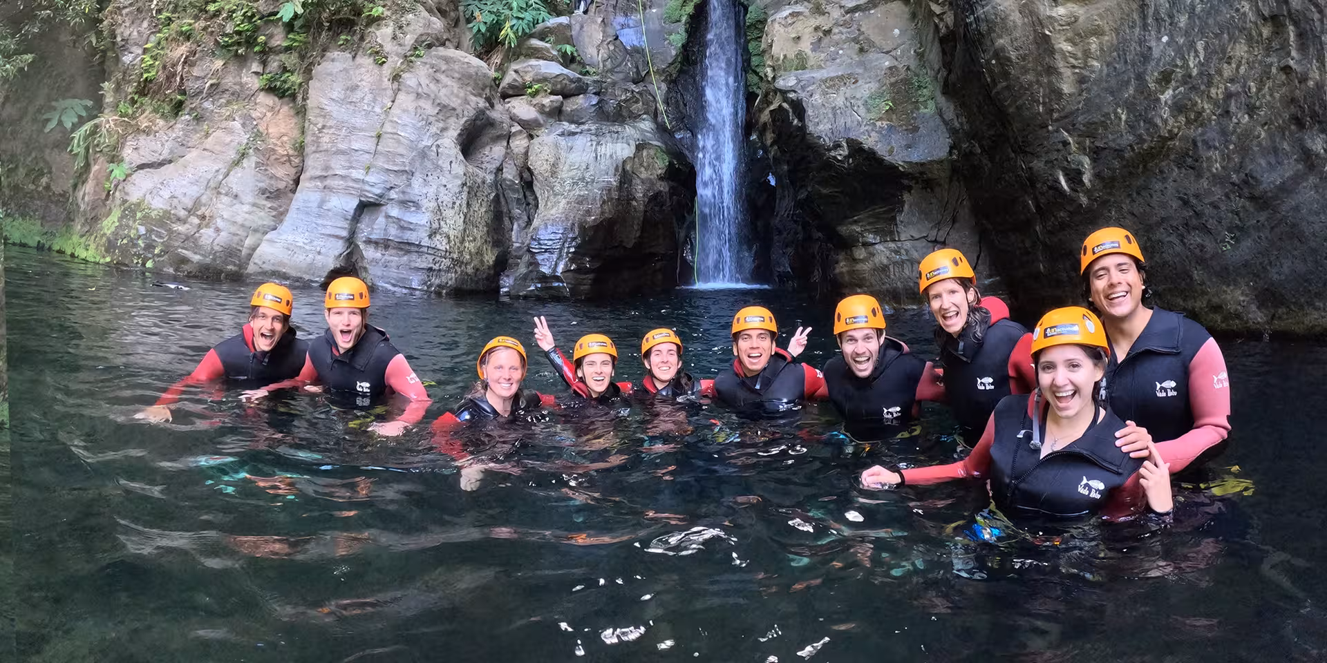 Group canyoning at Salto do Cabrito swimming in a natural pool below waterfall, São Miguel Azores tour