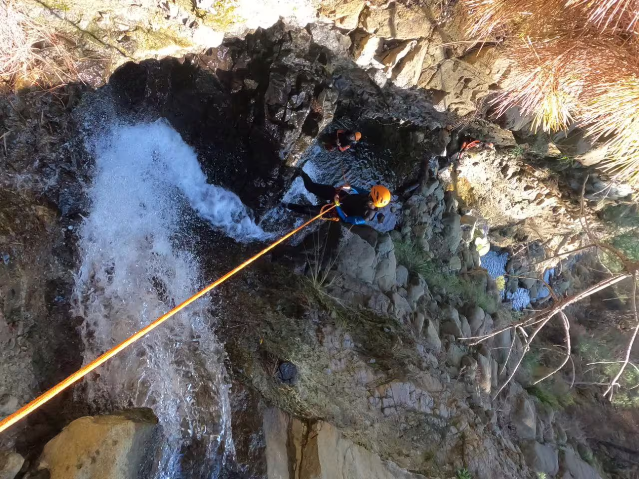 Adventurers canyoning down a waterfall in Sierra Bermeja, Estepona, showcasing thrilling outdoor nature exploration.