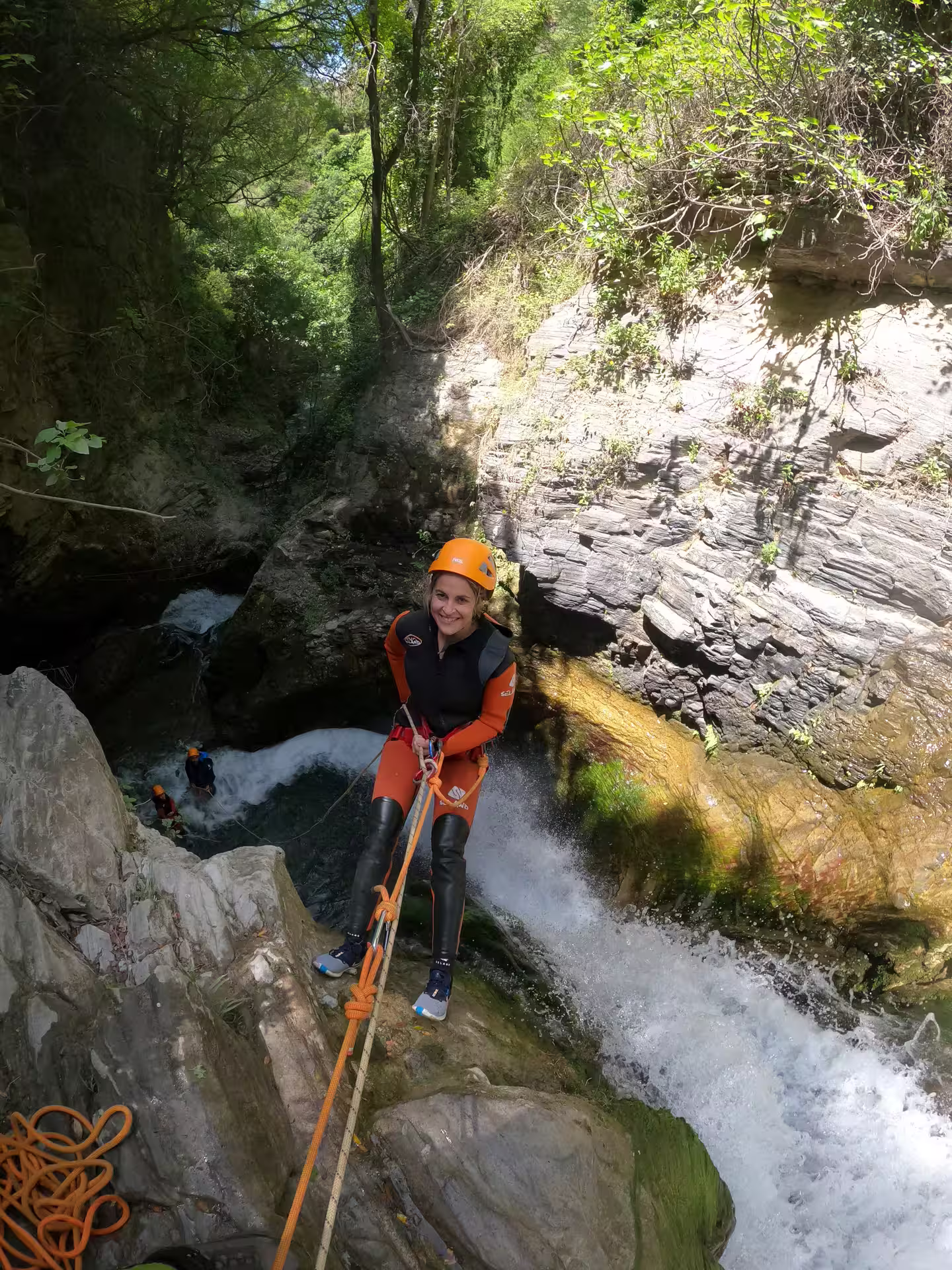 Adventurer rappelling down a waterfall during a canyoning tour in Sima del Diablo near Estepona, surrounded by lush greenery.