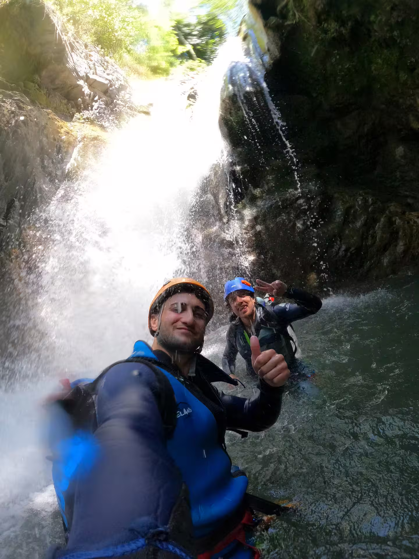 Adventurers enjoy canyoning in Sima del Diablo, near Estepona, Spain, surrounded by cascading waterfalls and rugged terrain.