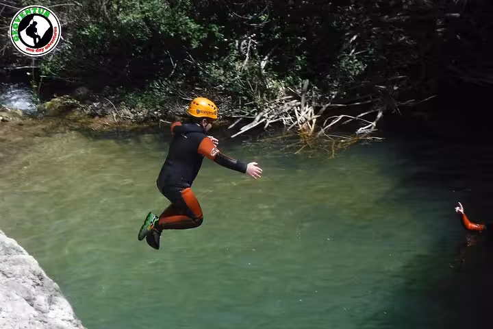 Canyoning in Teruel with guide-led jump into a clear river pool, wearing wetsuit and helmet in canyon
