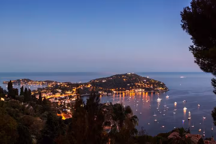 Twilight panorama of Cap Ferrat peninsula with twinkling lights reflecting on the Mediterranean Sea near Monte Carlo.