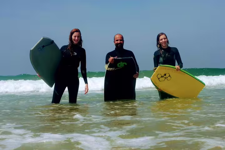 Group enjoying a thrilling bodyboarding adventure in Caparica, Portugal, with clear skies and refreshing ocean waves.