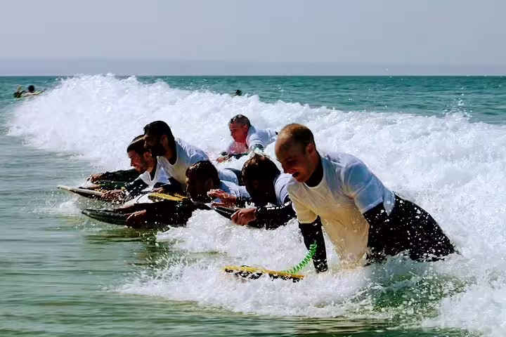 Group enjoying thrilling bodyboarding adventure on Caparica's scenic waves, perfect for outdoor enthusiasts and ocean lovers.