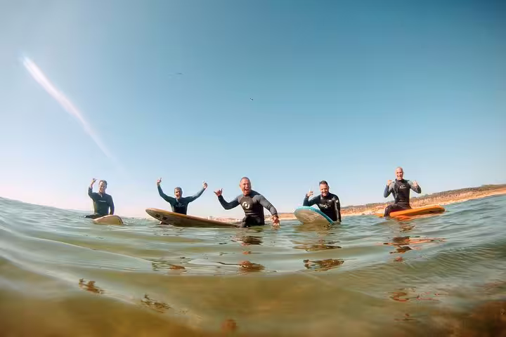 Group of surfers enjoying a sunny day on the water during Caparica Surf and Yoga retreat, ideal for adventure enthusiasts.