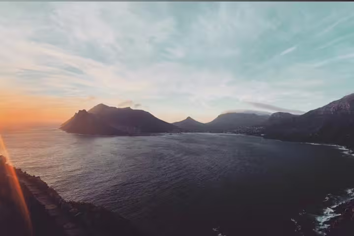 Stunning sunset view over the ocean at the Cape of Good Hope, highlighting the dramatic coastline and mountains.