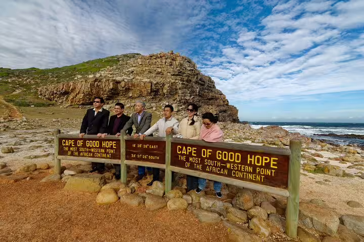 Visitors pose by the Cape of Good Hope sign, marking the southernmost point on the African continent's iconic coastline.