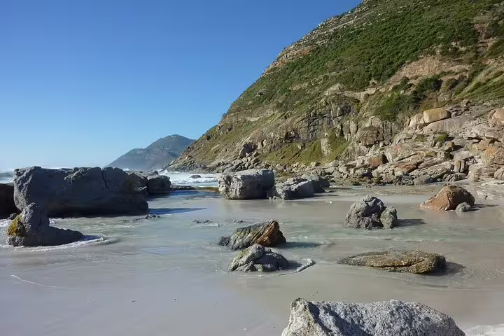 Rocky beach on Cape Peninsula day trip from Cape Town, with Atlantic waves and coastal mountains