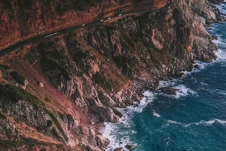 Scenic aerial view of the rugged coastline and winding road at Cape Point, highlighting the natural beauty of the area.