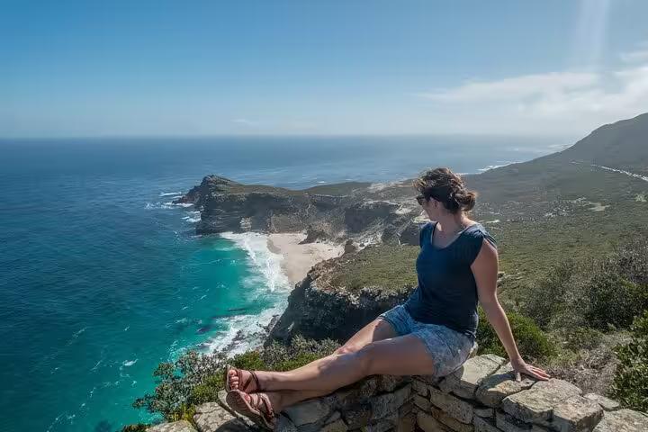 Visitor admires breathtaking views of Cape Point's rugged coastline and azure waters.