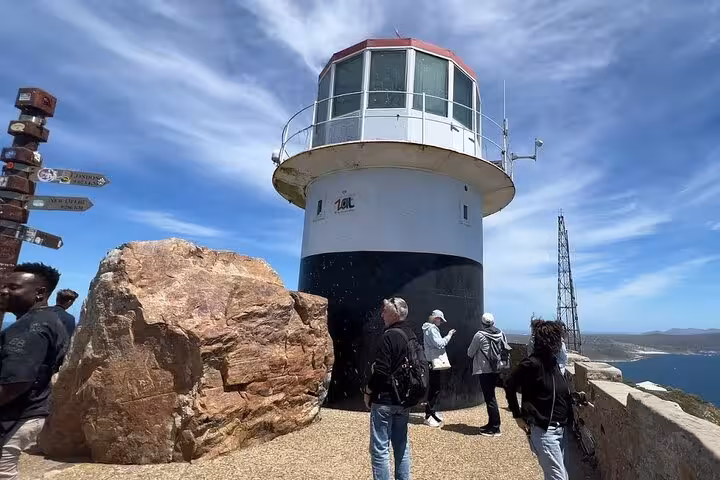 Tourists exploring the iconic lighthouse at Cape Point, offering panoramic views of Cape Town's coastline.
