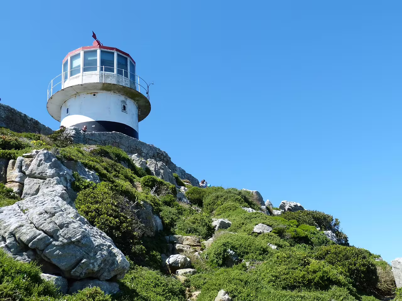 Historic Cape Point lighthouse perched on rocky hill with clear sky, a highlight of Cape of Good Hope tour.