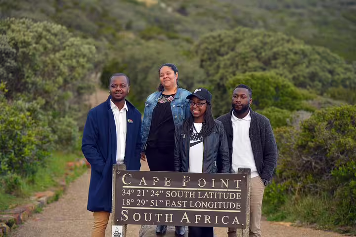Visitors pose at the Cape Point sign, capturing the scenic allure of a private tour from Cape Town.