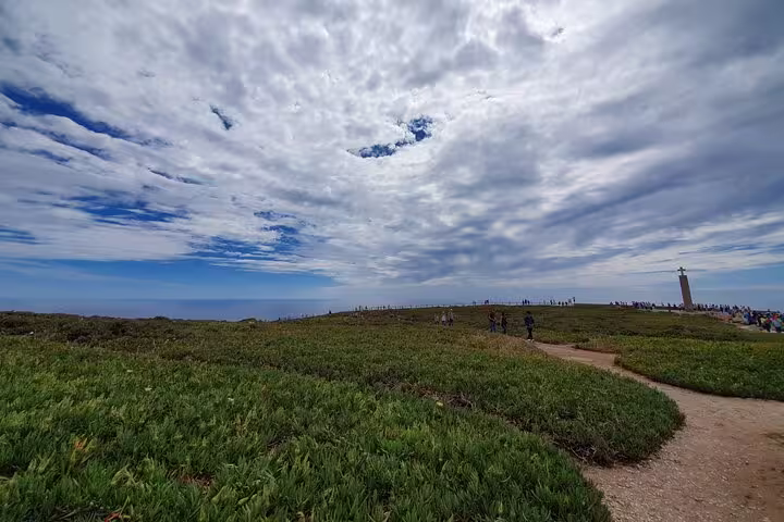Panoramic view of Cape Roca with lush green landscape and cloudy skies, part of the Sintra and Cascais tour.