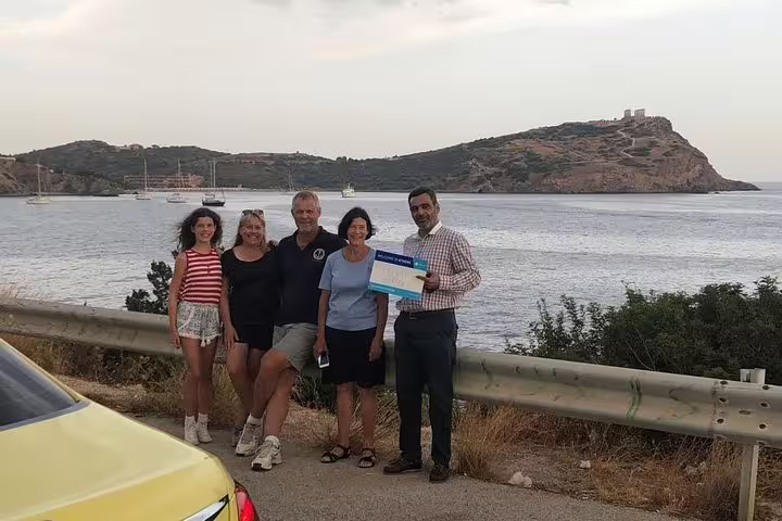 Tourists enjoying a scenic view of Cape Sounion with the Temple of Poseidon, during a day trip from Athens.