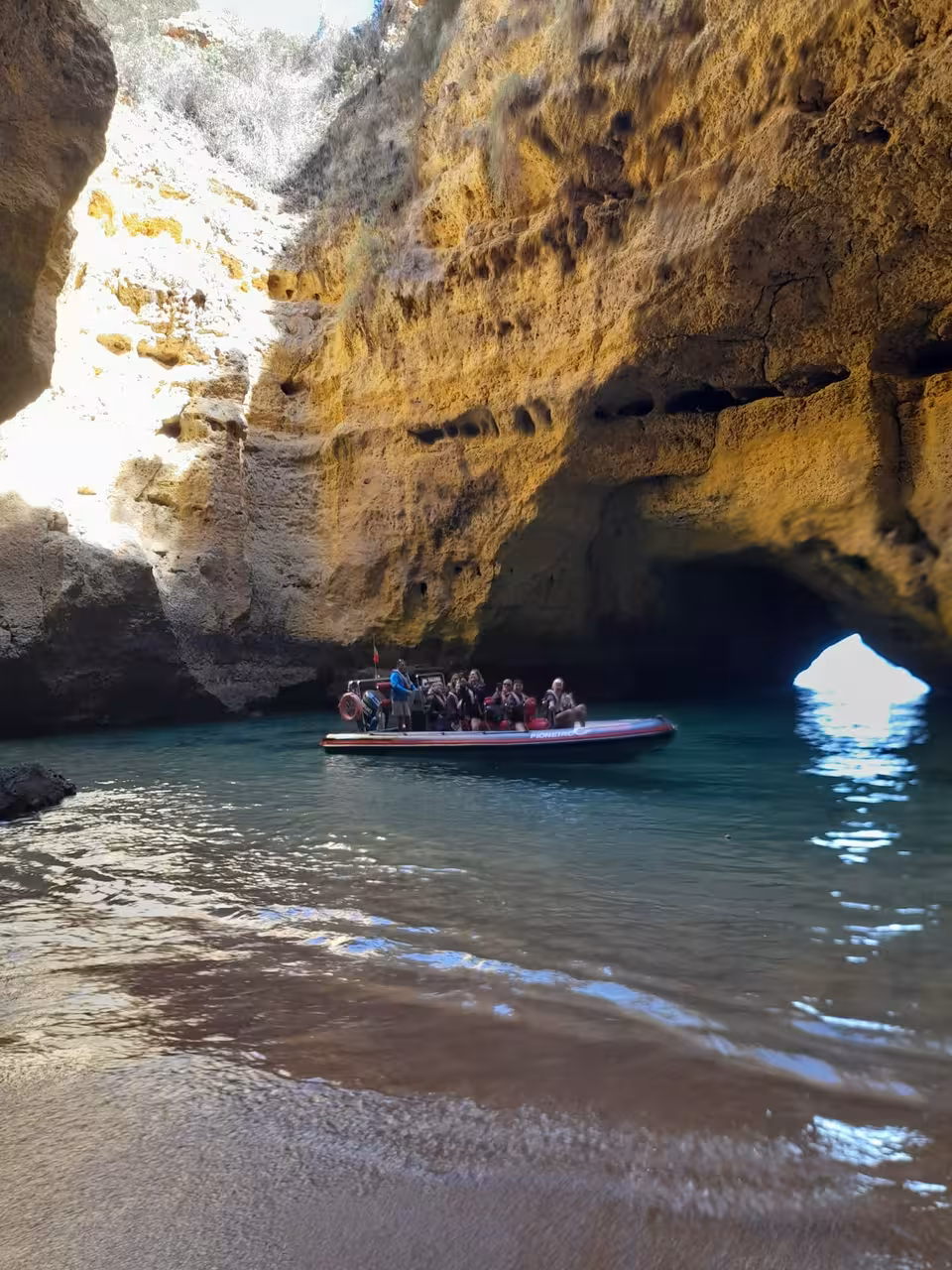 Tour group exploring Cape St. Vincent caves by boat, surrounded by striking rock formations and serene waters.