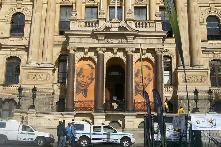 Historic Cape Town City Hall adorned with large portraits on a sunny day.