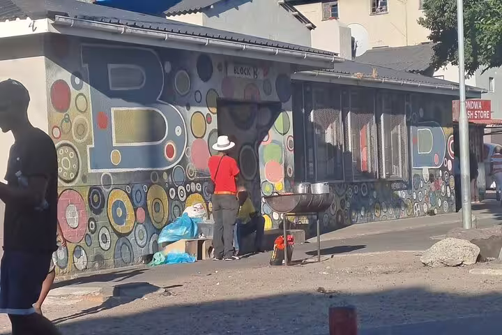 Street scene in Khayelitsha with vibrant wall art and local activity, part of Cape Town's township exploration tours.
