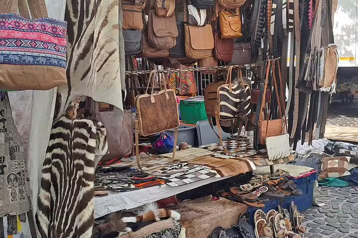 Vibrant market stall in Cape Town showcasing leather bags and animal print accessories, ideal for Table Mountain tour visitors.