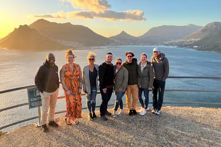 Group of tourists enjoying sunset views over Hout Bay during a Cape Town private chauffeur tour.