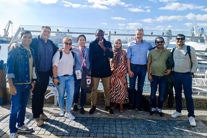Group of tourists at a waterfront in Cape Town, preparing for a Robben Island and Groot Constantia tour.