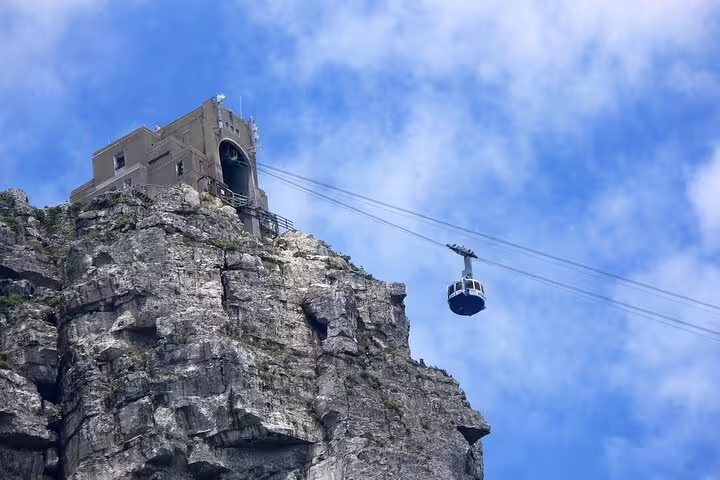 Cable car ascending Table Mountain against a clear blue sky on the iconic Cape Town tour.