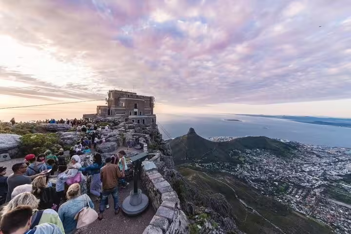 Tourists enjoy panoramic views from Table Mountain summit during Cape Town Essentials combo tour at sunset.