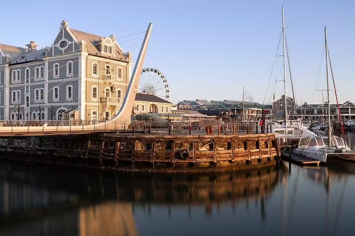 Scenic view of Cape Town's V&A Waterfront with yachts and iconic Ferris wheel, perfect for a full-day shopping tour.