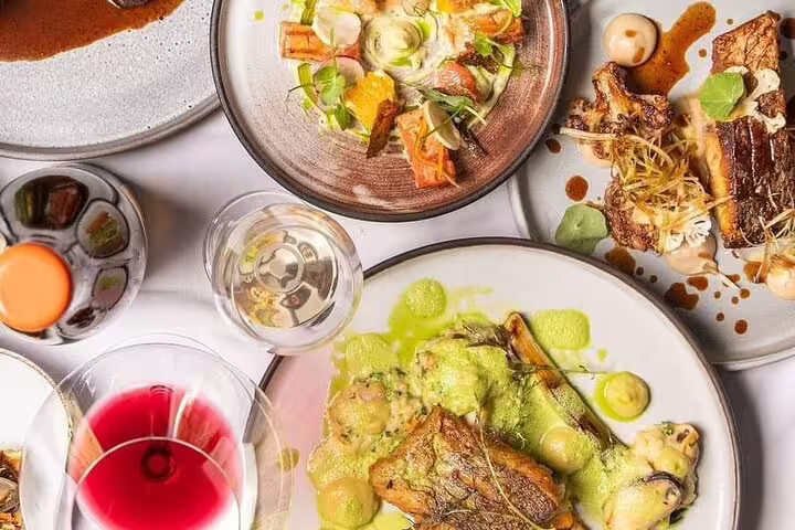 Aerial view of gourmet dishes with wine glasses at a Cape Town restaurant, highlighting culinary stops on the walking tour.