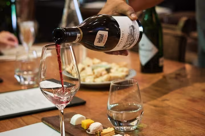 Pouring red wine into a glass with a cheese platter, showcasing a wine tasting experience in Cape Town's Winelands.