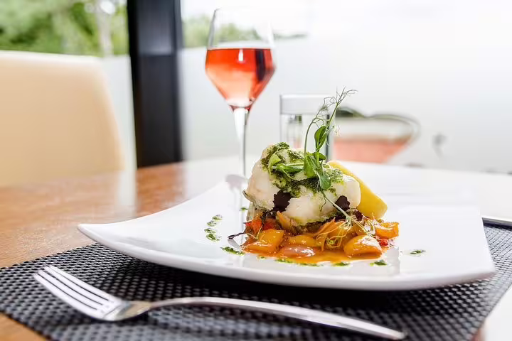 Gourmet dish paired with a glass of rosé wine, set in a serene dining space near Table Mountain.