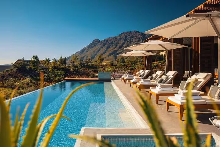 Luxurious Winelands retreat with poolside loungers and mountain views on a full-day Cape Town wine tour.