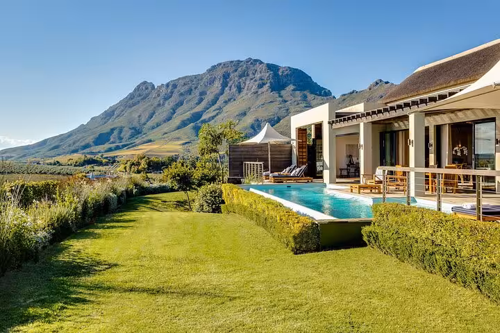 Luxurious villa with pool overlooking scenic mountains and vineyards on a Cape Town Winelands tour.