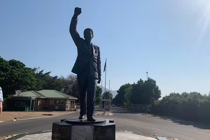Statue with raised fist on a sunny day at the entrance of a historical site in the Cape Winelands region.