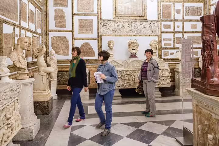 Visitors exploring classical statues and inscriptions inside the Capitoline Museums in Rome during a private guided art history tour