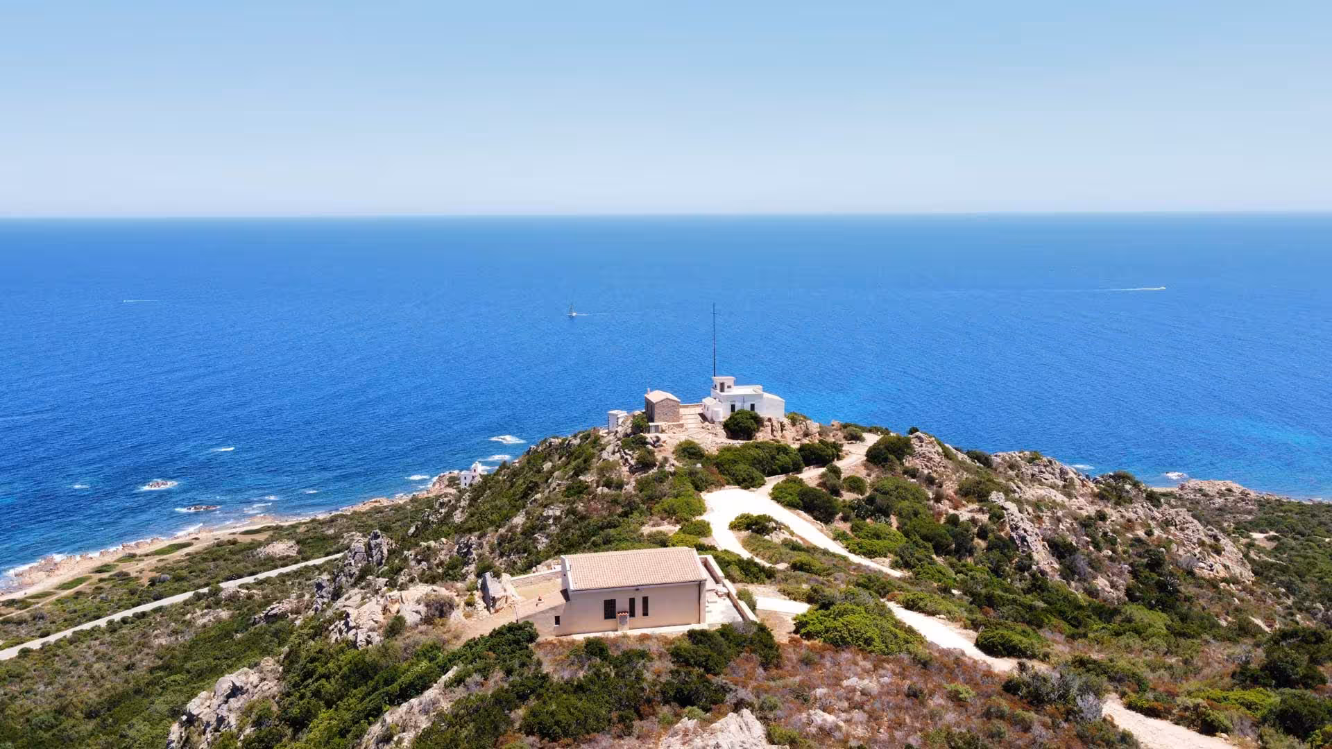 Aerial view of Capo Comino's rugged coastline and azure sea, highlighting the picturesque landscape of Sardinia.