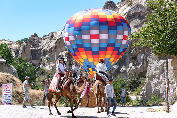 Camel ride beside colorful Cappadocia hot air balloon before flight tour from Istanbul with overnight stay