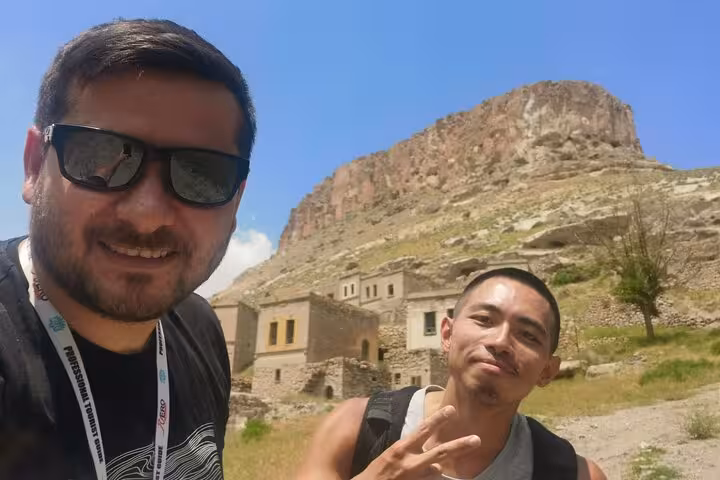 Guests selfie at ancient cave village beneath volcanic cliffs on Undiscovered Cappadocia private day tour