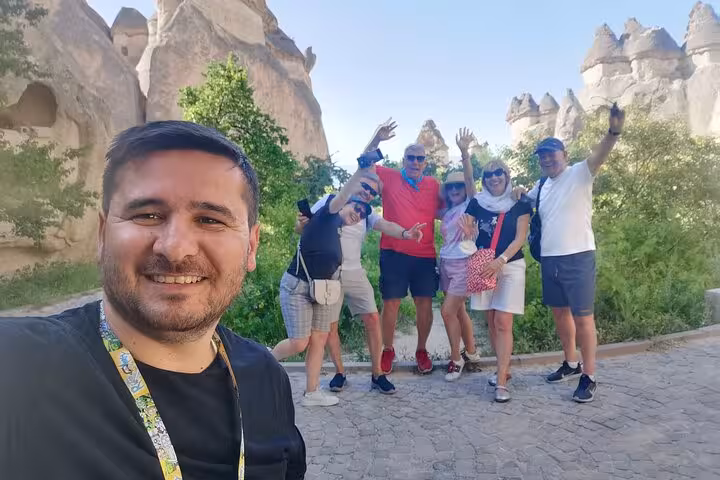 Private Cappadocia tour from Istanbul with guide and travelers posing by fairy chimneys in Göreme Valley