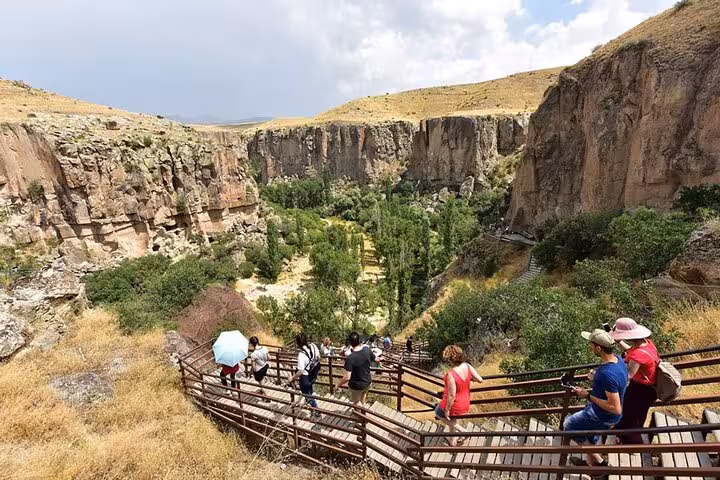 Tourists descending wooden stairs into Ihlara Valley canyon on Cappadocia Green Tour with lunch and hikes